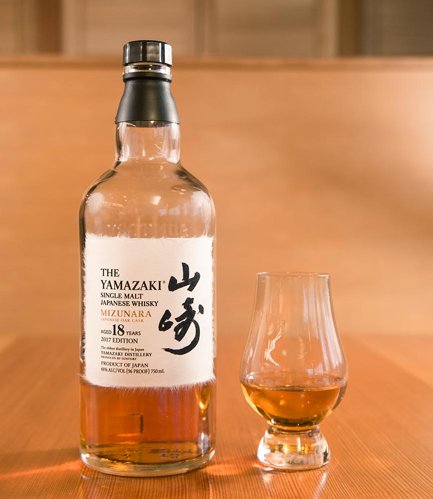 A bottle of Yamazaki 18 Mizunara and a Glencairn whisky tasting glass.