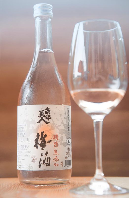 A bottle of Japanese plum wine and a wine glass.