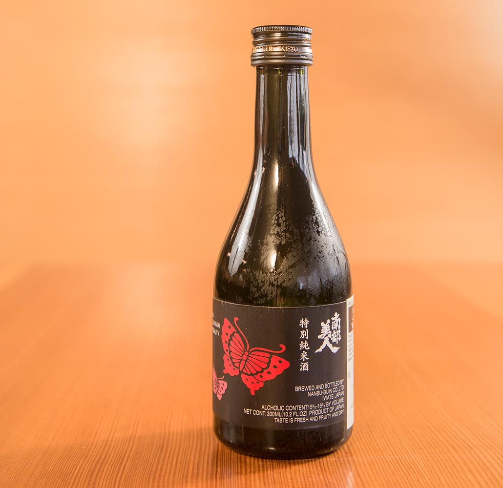 A bottle of Japanese sake in a wooden kappo restaurant setting.
