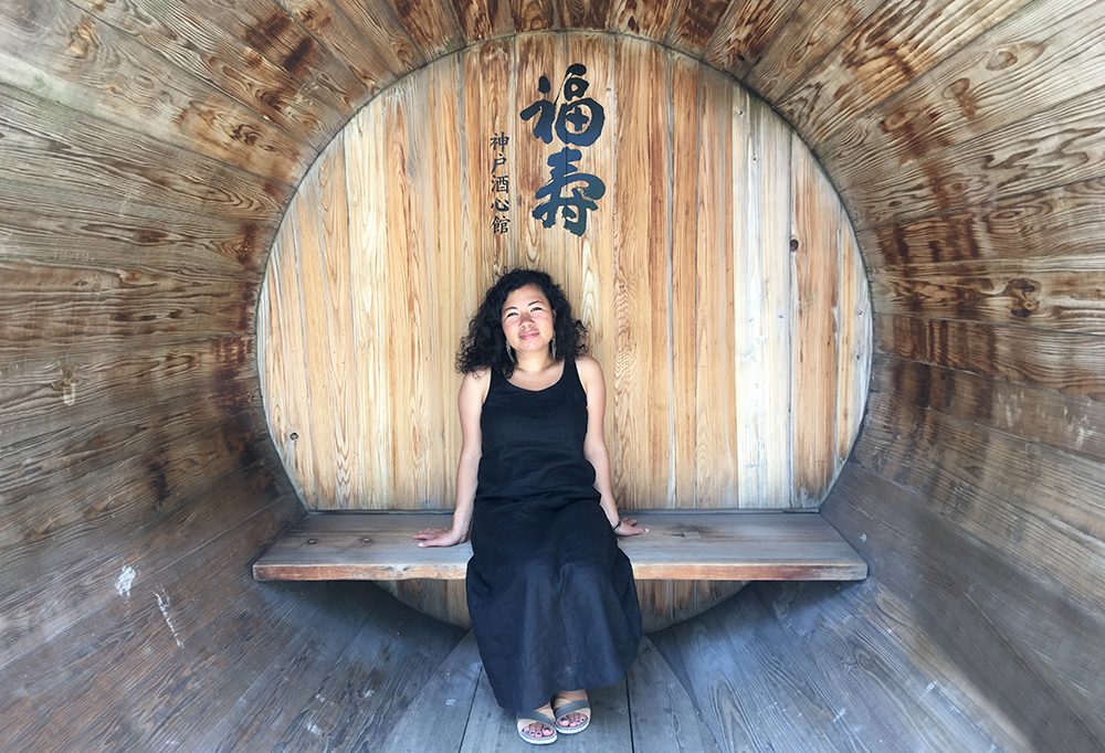 a woman sits inside a huge wooden sake cask