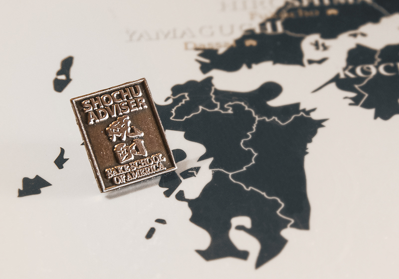 a beverage certification pin resting on a map of Japan