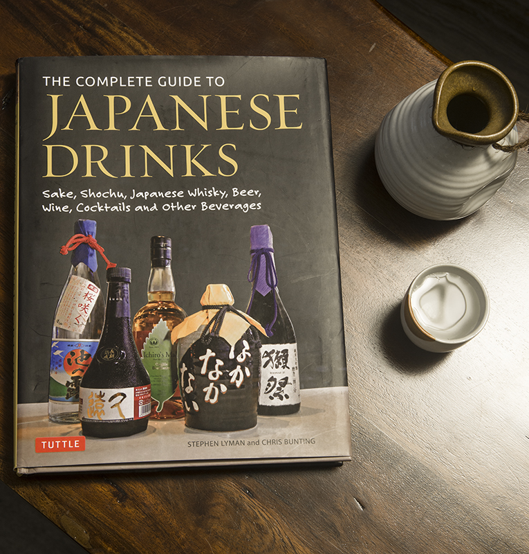 a book about Japanese alcoholic beverages next to a sake carafe and cup