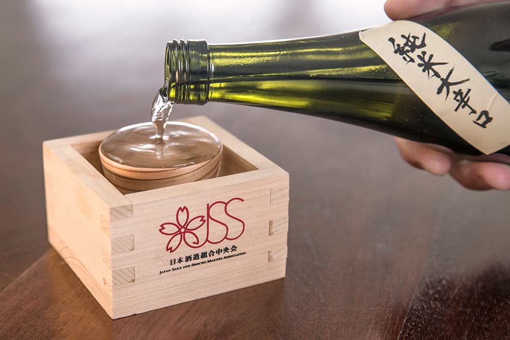 Sake being poured into a wooden box (a masu)