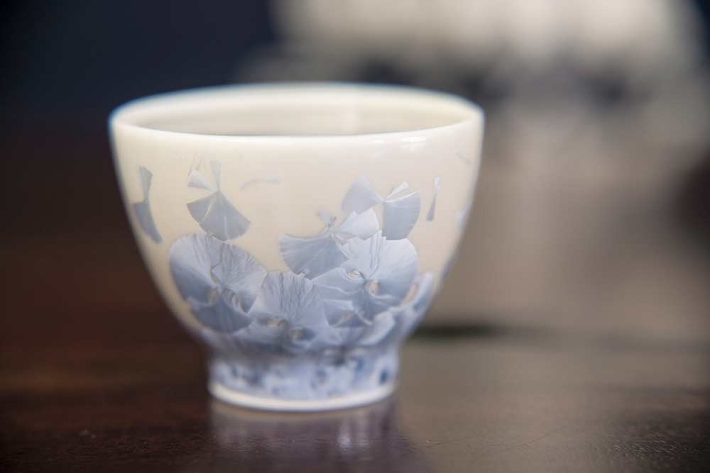 a small ceramic sake cup with blue shell overlay