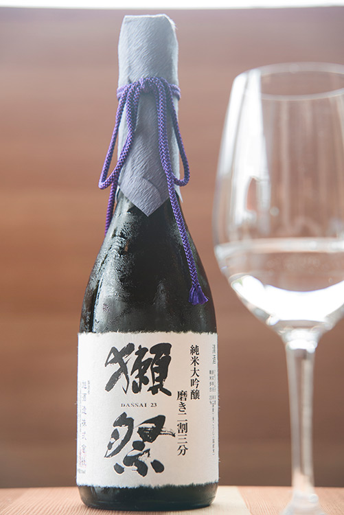 a bottle of sake and a wine glass on a wooden table
