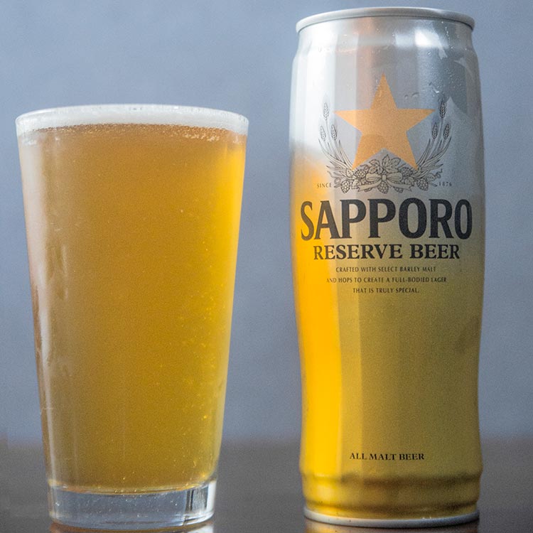 A large can of Sapporo beer and a pint glass