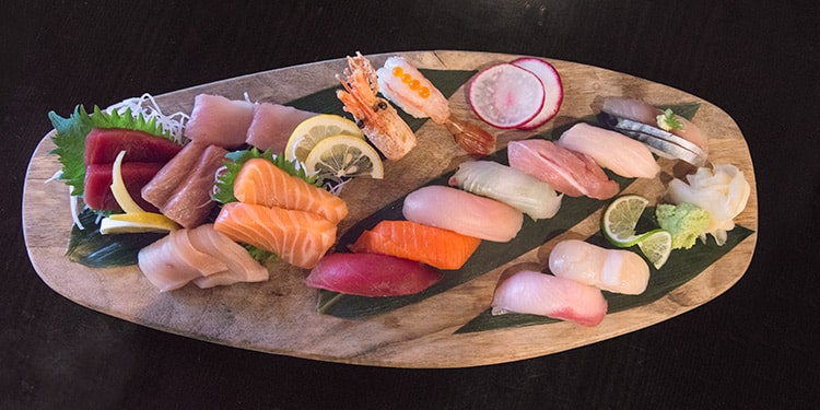 a platter of sushi and sashimi on a wooden board