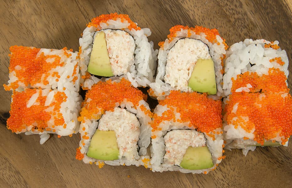 a sushi roll with fish roe on the outside and crab inside
