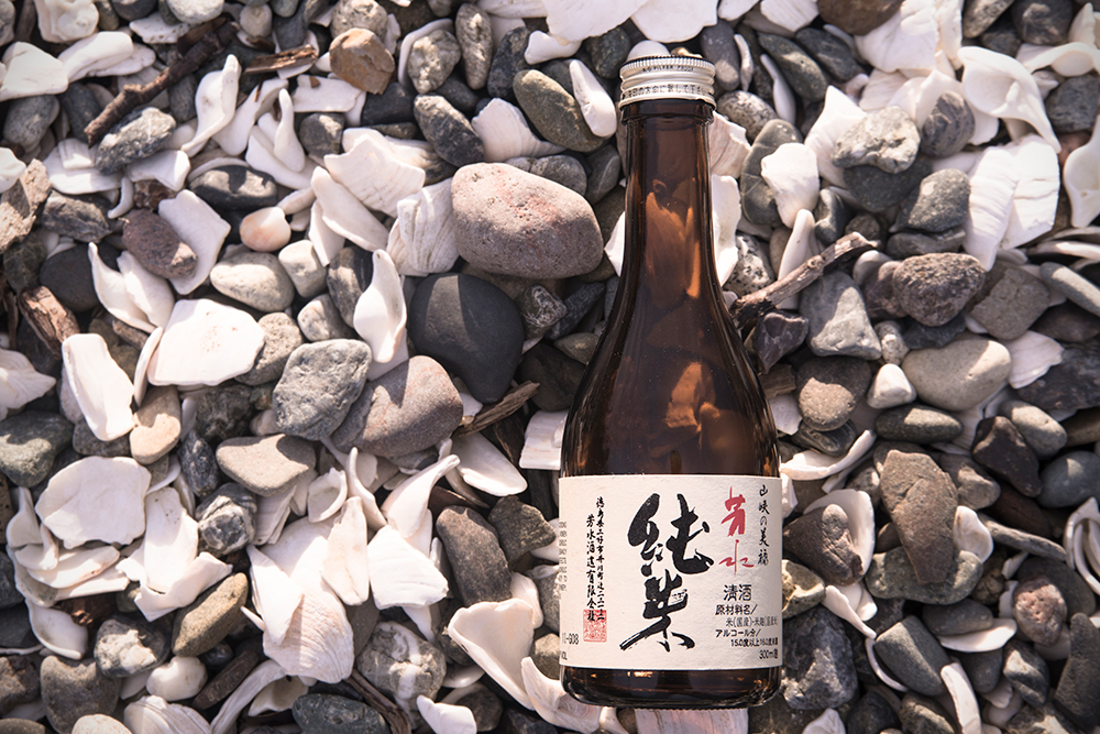 a bottle of sake on crushed oyster shells