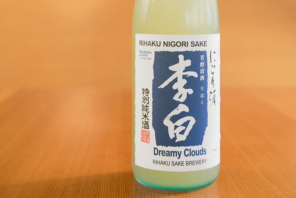 a blue-green bottle of sake in a wooden room
