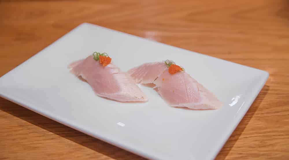 two pieces of albacore sushi topped with mimiji and scallion