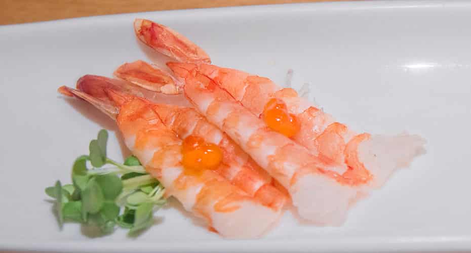 two pieces of shrimp sashimi with salmon roe on top