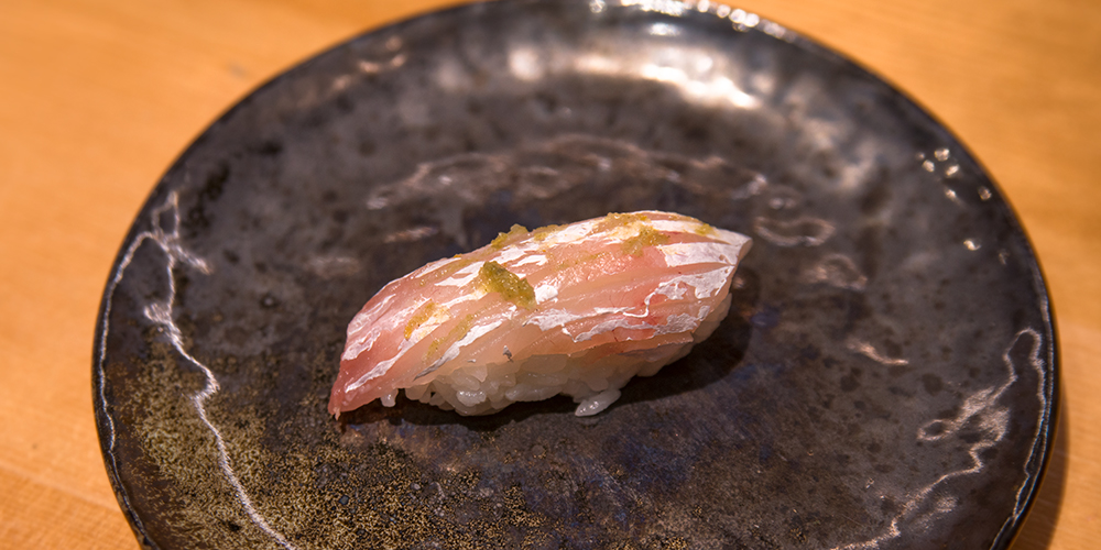 a piece of madai nigiri topped with yuzu kosho