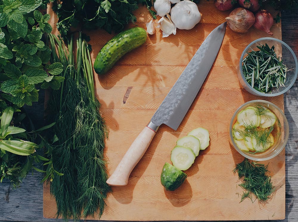 a Japanese knife with vegetables on a cutting board