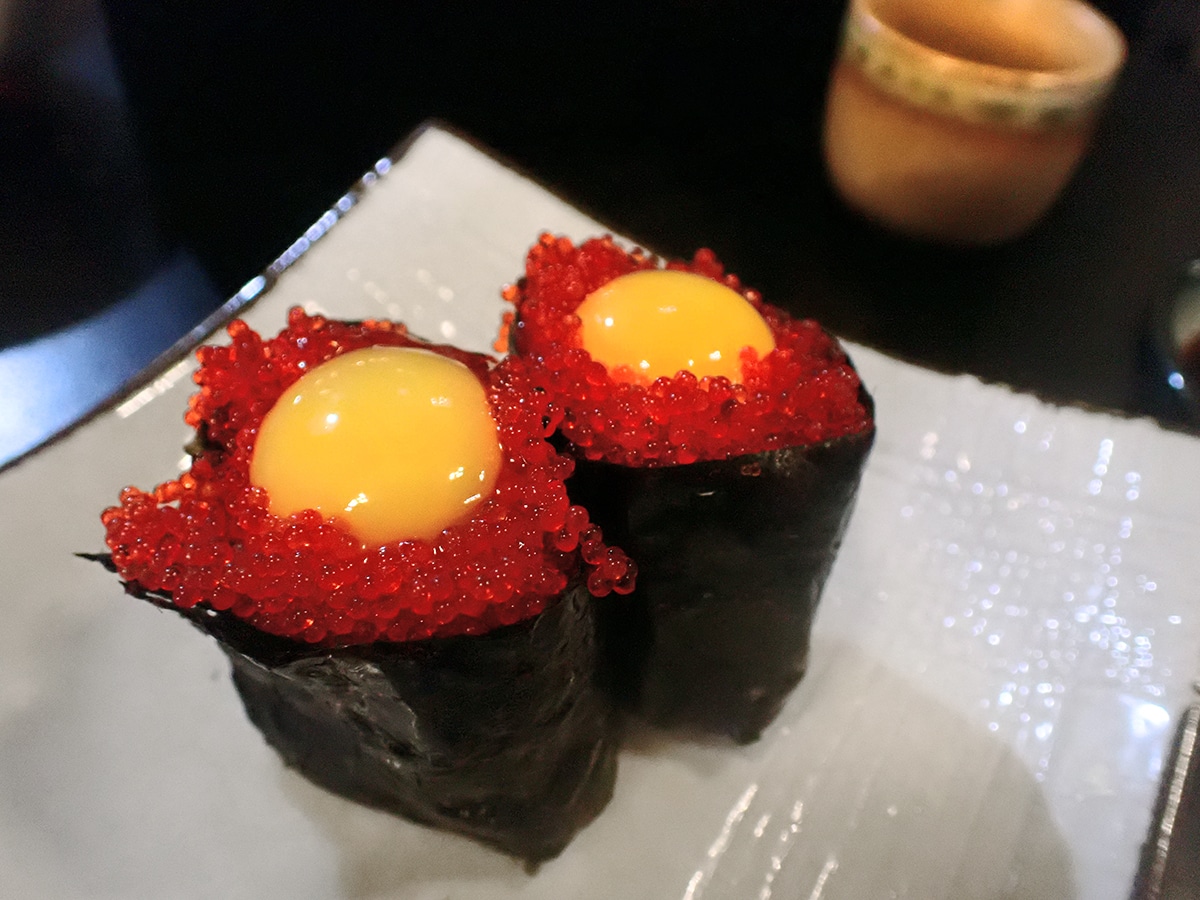 two pieces of red fish egg sushi with egg on top