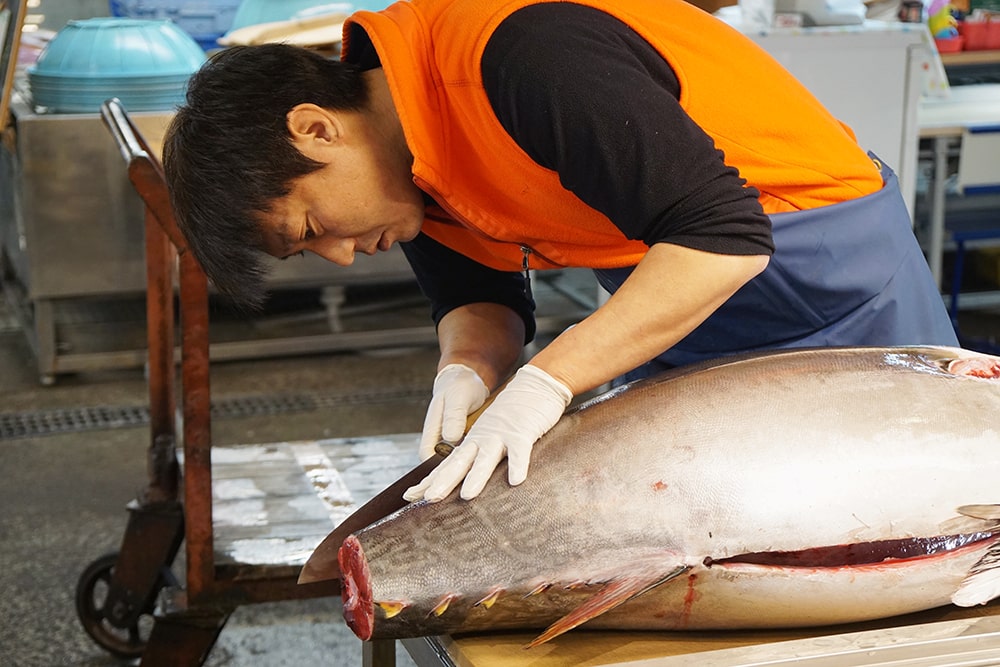 a fishmonger butchers a Pacific bluefin tuna