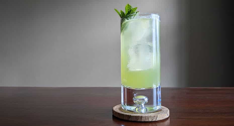 a virgin mojito in a highball sits on a wooden table