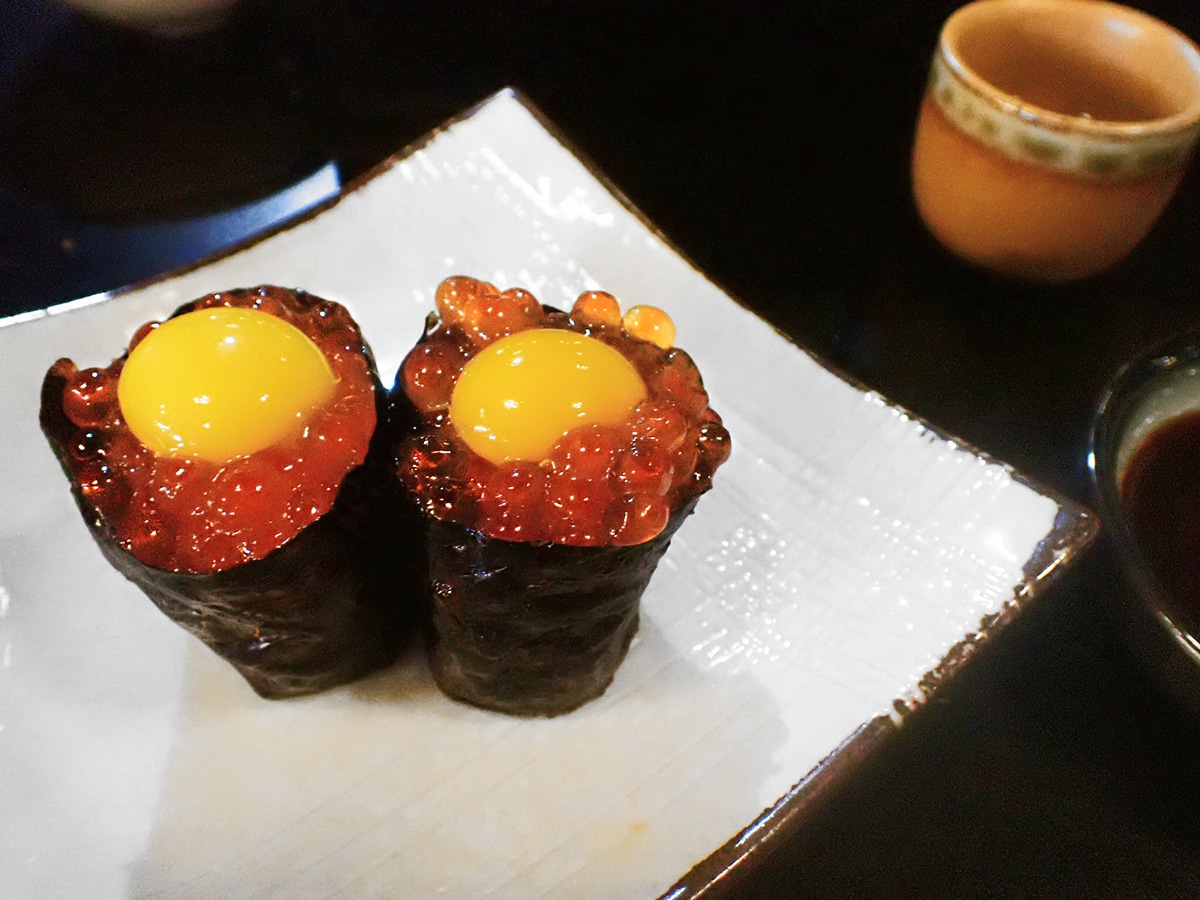 two pieces of salmon egg sushi with quail egg on top 