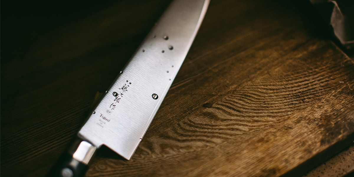 a shiny Japanese knife on a wood cutting board